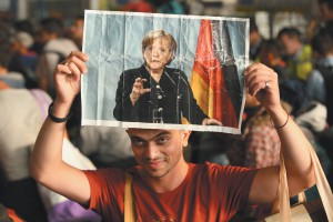 A Syrian refugee holding a picture of German Chancellor Angela Merkel as he and hundreds of other migrants and refugees arrived in Munich from Hungary, September 2015
